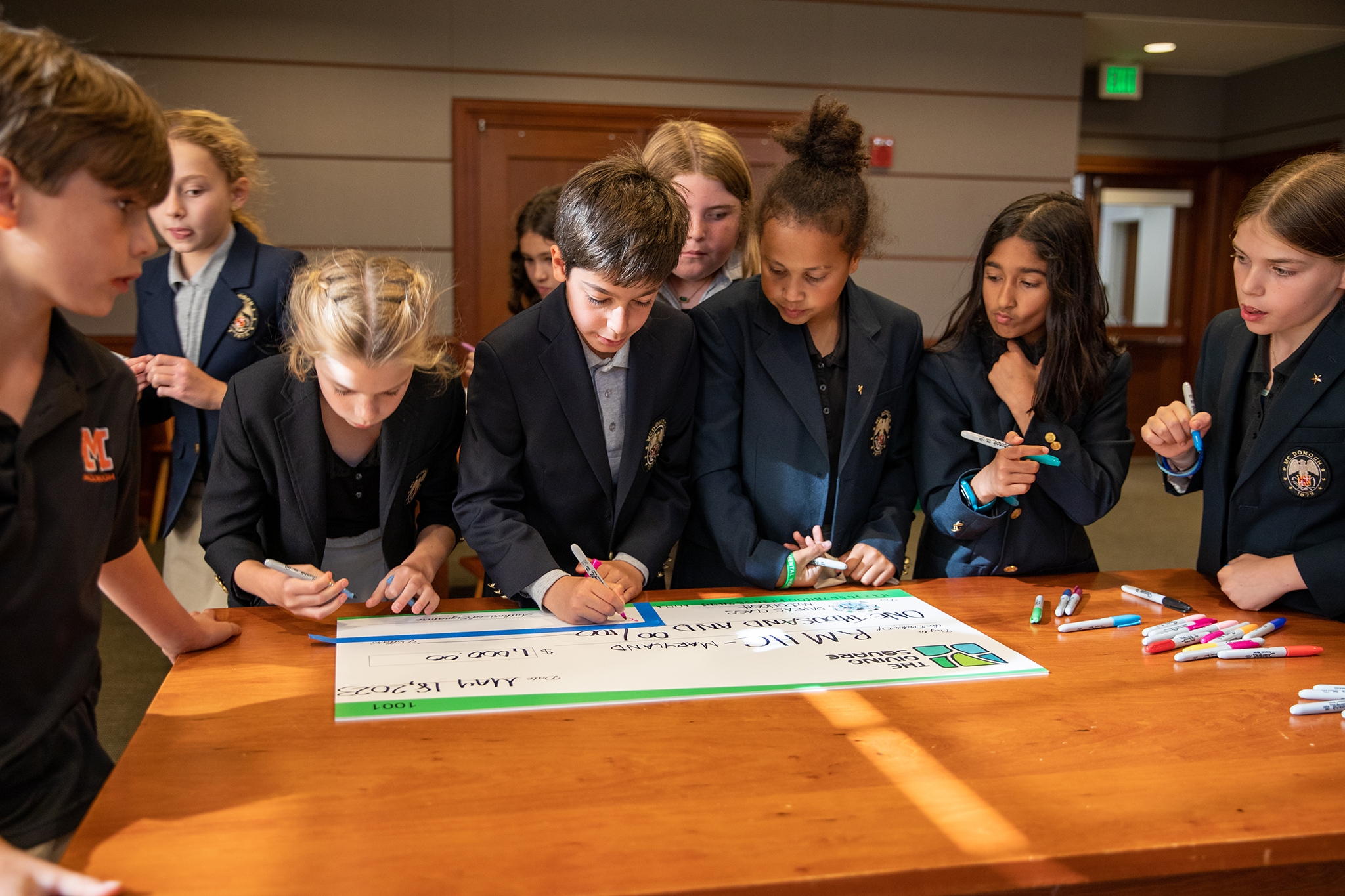 4th-grade students in the Greatest Good McDonogh program, working with The Giving Square, sign their cohort’s donation to Ronald McDonald House Charities Maryland.